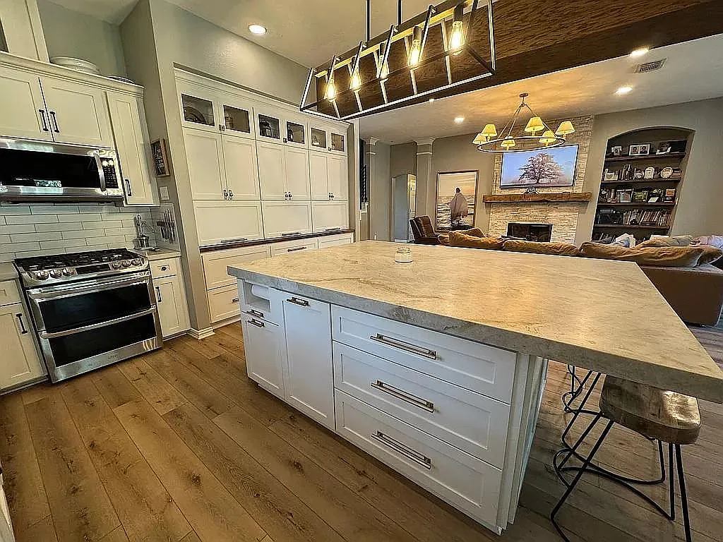 Kitchen island, white cabinets and adjoining living room at 27103 Bridleway Circle in Magnolia, Texas