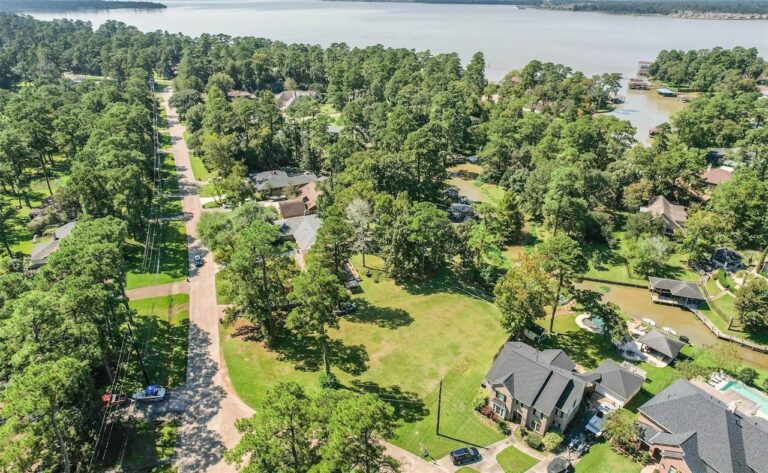 Aerial listing photograph of the vacant lot at 2034 White Feather Trail in Crosby, with neighboring homes and the surrounding waterway